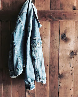 A jean jacket hanging up on a hook