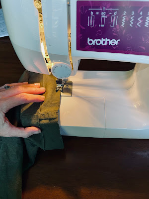 A hand and fabric at a sewing machine